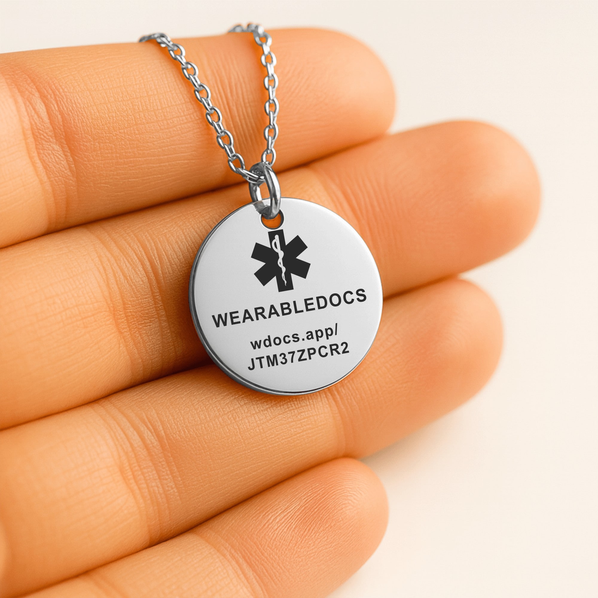 The back of the coin pendant, engraved with the Star of Life, WEARABLEDOCS and the web address.